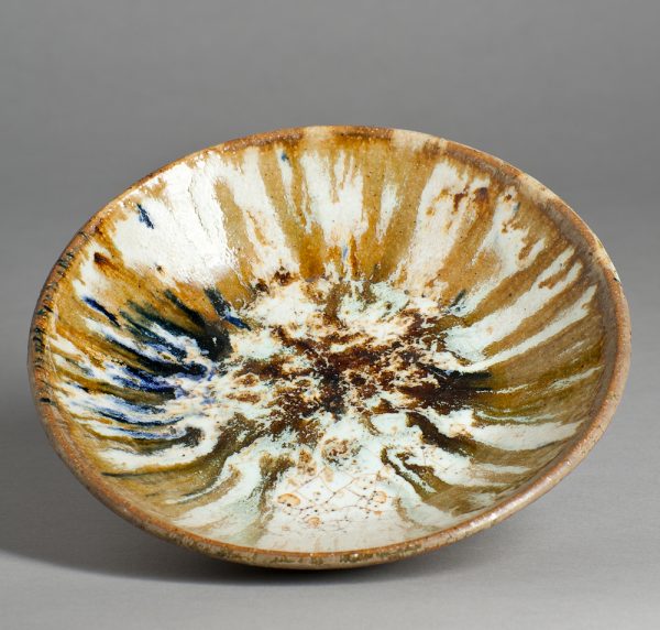 A stoneware plate varigated tans and blues over white.