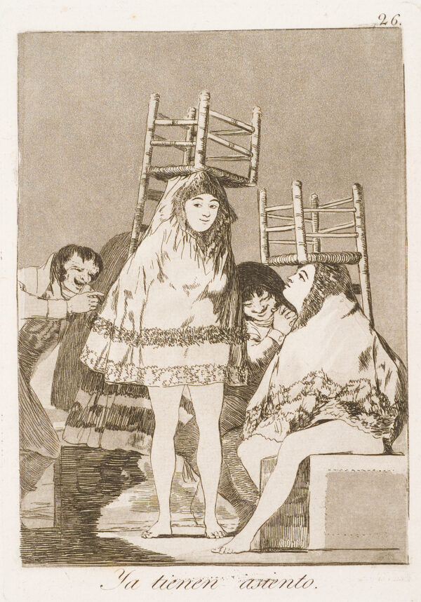 Two women with chairs up-side-down on their heads, are laughed at by the two men.