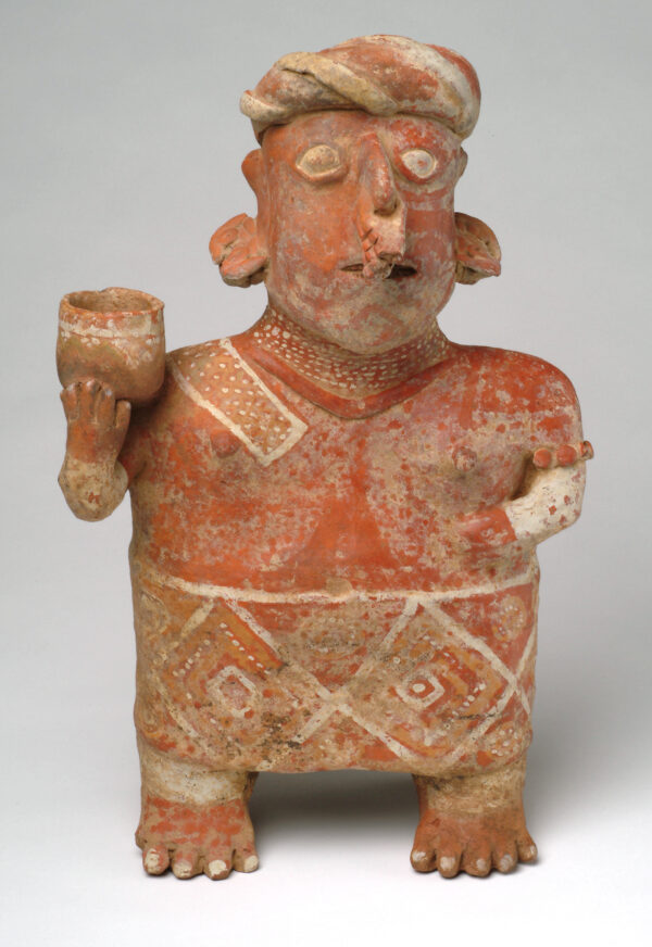 Standing lady with her right arm raised. Red with incised geometric patterns on dress.