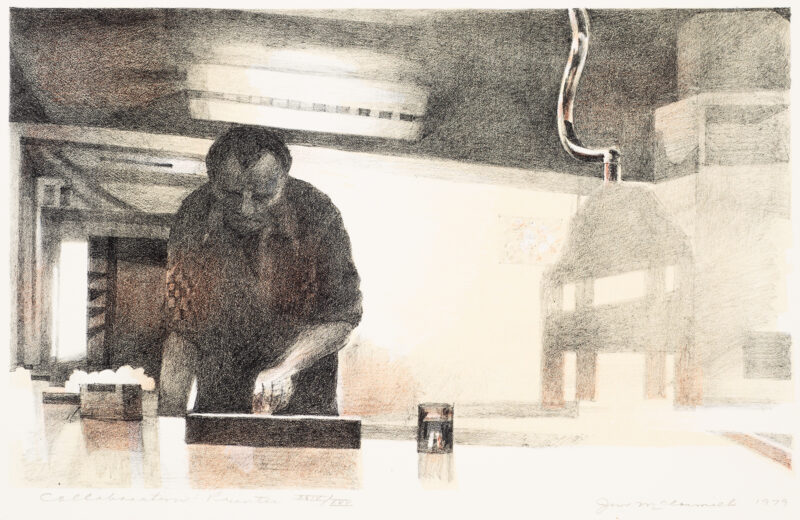 A man stands inking a plate next to a printing press.