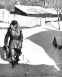 A woman is walking in the snow in town.