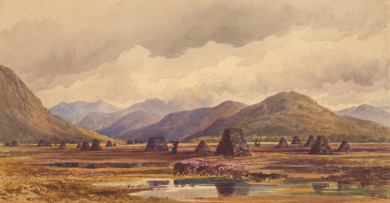 A landscape with water in foreground and peat stacks behind.