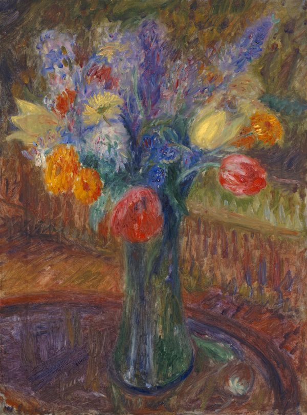 A still life of red, blue and yellow flowers in a green vase, sitting on a round table.