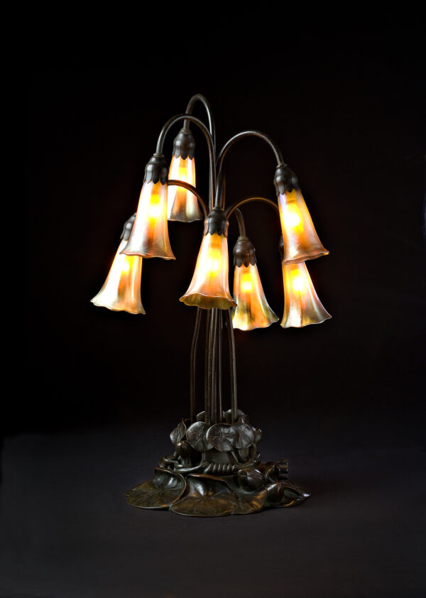 Seven pendant shades in the form of lillies in favrile glass with a bronze base of water-lily pads.