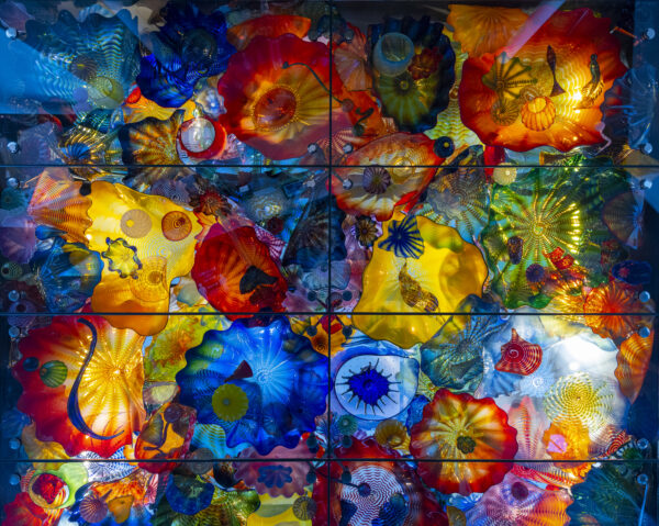 More than two dozen round-like forms of blown glass set together in multiple colors, including red, blue, green, yellow and purple