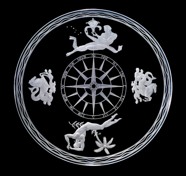 # 0054 A wide, shallow bowl of clear crystal, engraved with the theme of a compass rose. In the center is the dial of the mariner's compass. Surrounding it are four decorative groups. To the north a bearded man holds an elaborate fleur-de-lis, the traditional symbol of this point of the compass; the stars of the Big Dipper point toward it. To the south is a woman reclining under a palm tree. To the east and west sea horses rear above the ocean. The outer edge of the bowl is engraved with a wave motif.