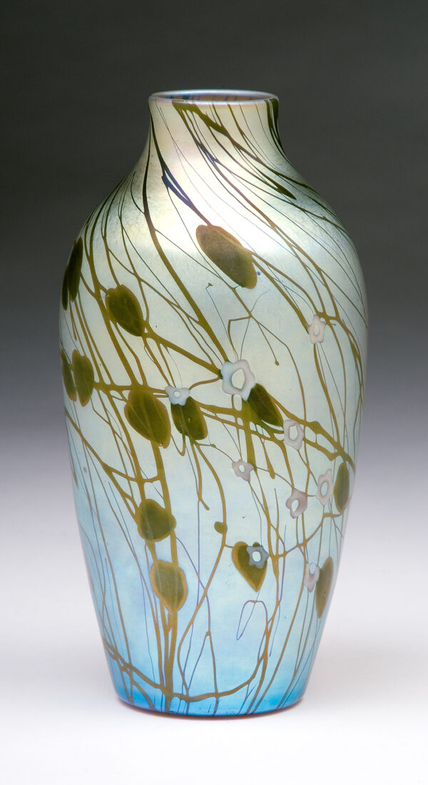 Shape # 596. Cylindrical vase form in iridescent gold decorated with green hearts, vines, and white millefori clusters.