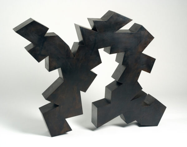 Two sides of the sculpture are flat, the sides, top and bottom are cut in various geometric angles.