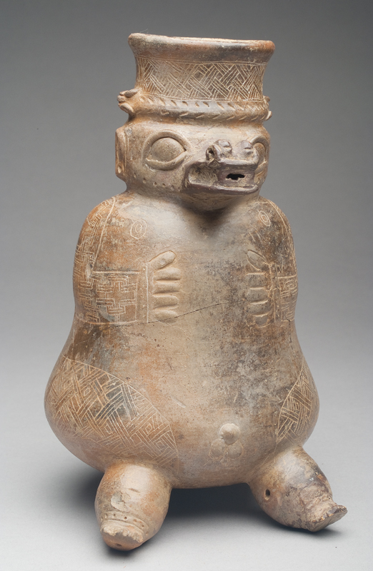 Buff body. Figure is has a three-dimensional head and feet with an additional head for the third foot. There are geometric incised lines for the arms, lower body and neck of vessel.