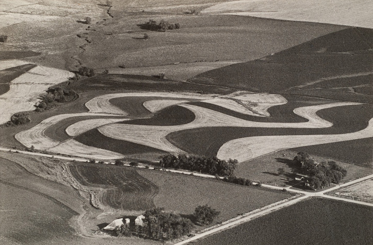 Two roads cross in lower right with rounded cultivated fields at the center.
