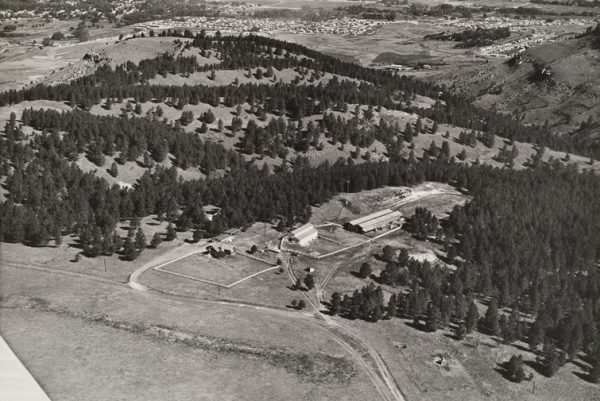 A farm with small town in background. The plane’s wing is visible at bottom left.