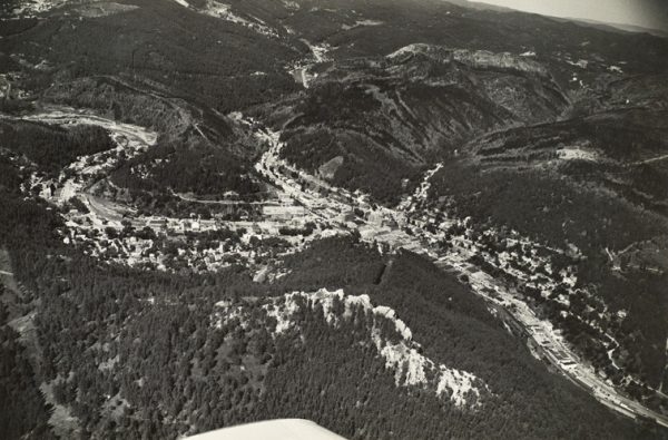 Town in tree-covered rolling hills. The tip of the plane’s wing is visible at lower center.