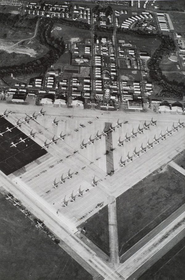 Planes are lined up on a triangular shaped tarmac.