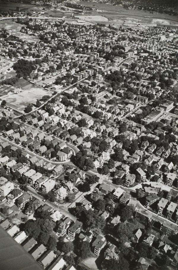 Houses and tree with wing of plane visible in lower left corner.