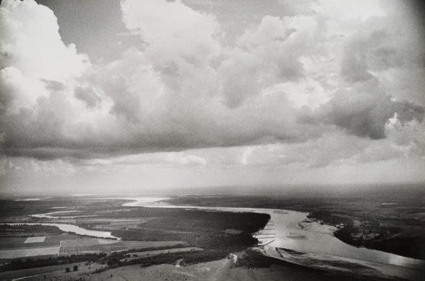 A river snakes into the distance with a cloudy sky and fields on each side.