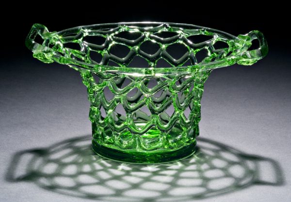 Shape #644. An open work basket in an inverted hat shape with two handles and solid, flat bottom in apple green glass.