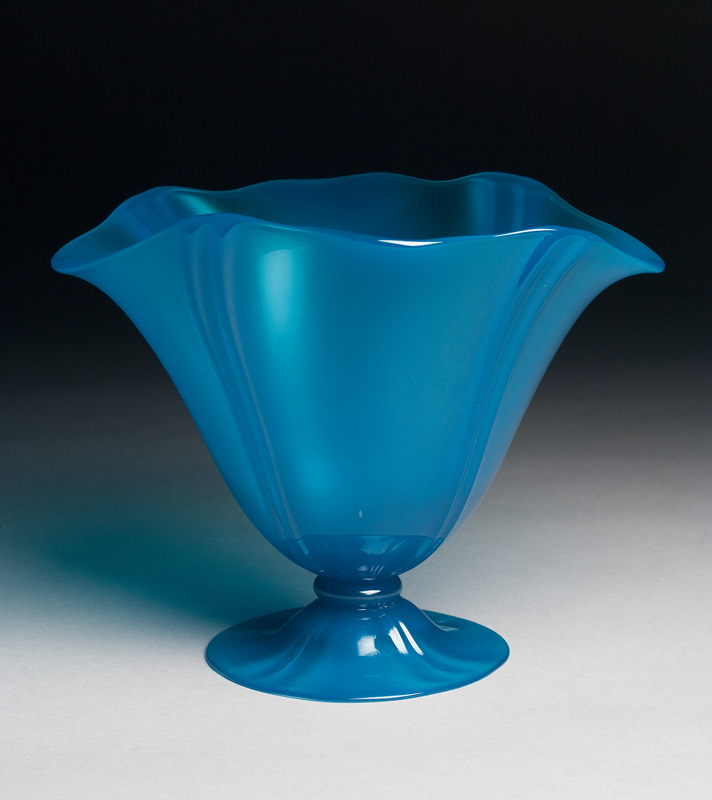 A blue vase with flared foot and four pairs of vertical ribs in a wavy shape.