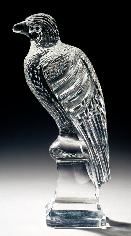 A stylized bird sitting on a pedestal. The feathers on the bird are geometric lines carved into a blocky form.