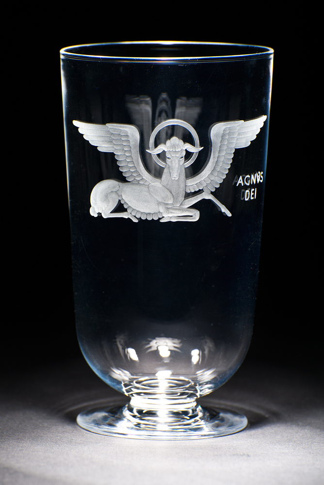 A clear glass vase with  image of winged ox, the symbol of the Christian evangelist St. Luke. The vase was designed for the National Cathedral in Washington, D.C. 
Agnus Dei (Lamb of God) refers to Jesus Christ in his role of the perfect sacrificial offering that atones for the sins of humanity in Christian theology.