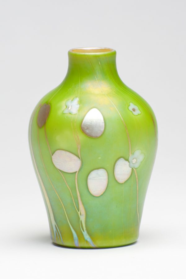 Shape #571. A green vase with iridescent leaf and stem shapes with white flowers. The interior is gold Aurene.