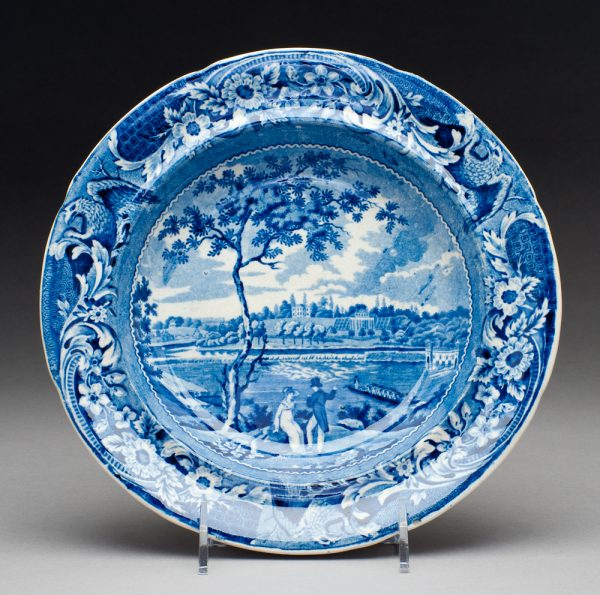 Fair Mount near Philadelphia.	A blue transfer of a couple beneath a tree, a river with a boat being rowed by soldiers and buildings on the far shore.
The designer was Joseph Stubbs (identified by the three eagles and scrolls/flowers on border.)  View in the center is based upon a drawing by Thomas Birch, engraved by R. Campbell.  Published by Edward Parker, 1824 called View of the Dam and Water Works at Fair Mount, Philadelphia.  Water works were constructed in 1813.