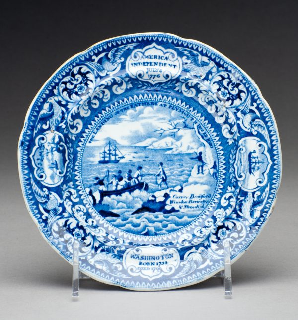 In blue transfer, The Landing of the Fathers of Plymouth December 22, 1620 a small boat is offloading onto shore, from the large sailing ship in the distance.