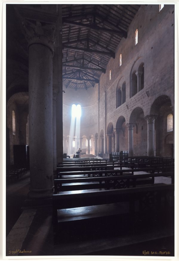 Sant' Antimo's Abbey in Tuscany, Italy as seen from the back, looking toward the front, where a single priest is 