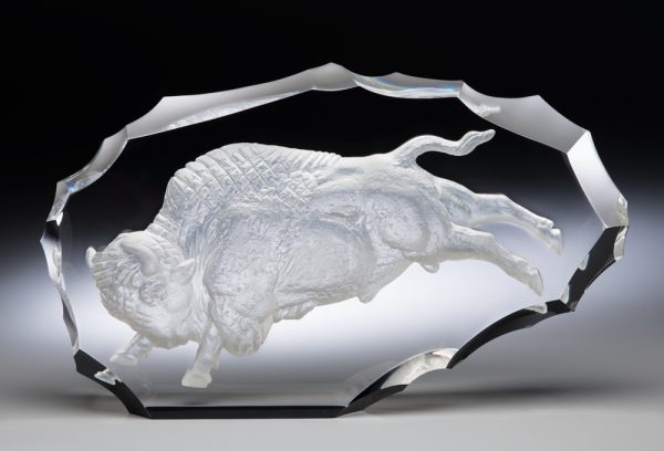 #X4324, Crystal cut to resemble an American Indian's primitive tool, flaked away around the edges. The bison is cast in profile, his legs extended, his massive head lowered.