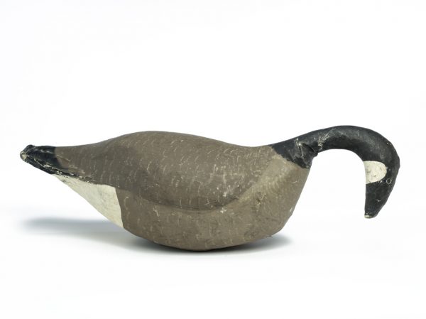 A goose decoy with gray body, black neck, beak and tail, white below tail and below head.