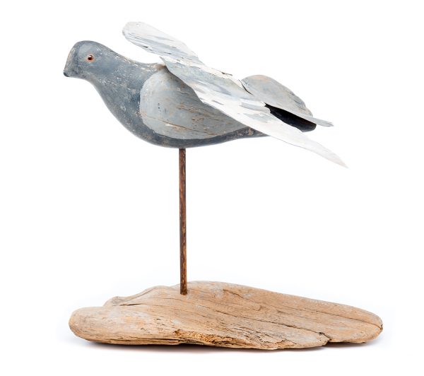Painted wood decoy with painted sheet metal wings outstreched, supported on driftwood base. Glass eyes.