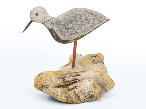 A painted wood decoy mounted on a driftwood base. The plover has an iron beak and nails for eyes.