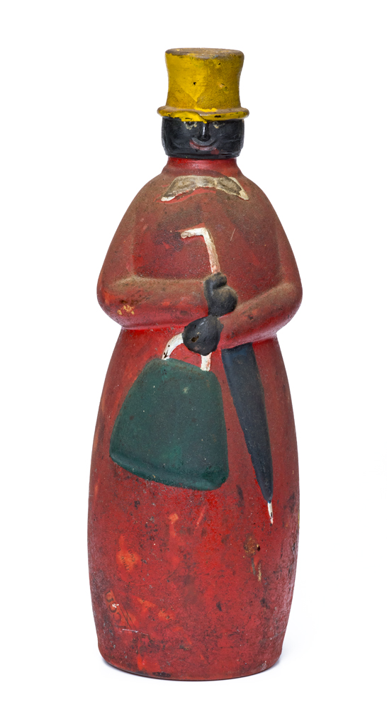 A figure made of a cast glass bottle with a painted surface. The bottle is filled with sand. The doll wears a red outfit with grey bow tie, and yellow top hat. It also has a green bag and black umbrella.