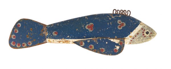 A small fishing lure with carved wooden body and metal fins and tail. It is painted overall with blue, red, white, and silver-grey paint. A series of iron-alloy loops are present on the top of the body. There is a lead weight embedded in the underside of the body.