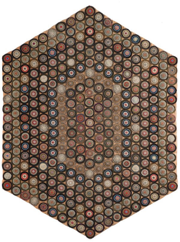Multi-colored rug with felt penny cutouts on black all on tan/rose color background