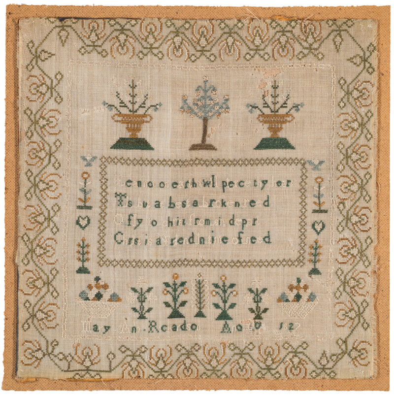 Wide embroidered border. Center has two baskets, tree at top center