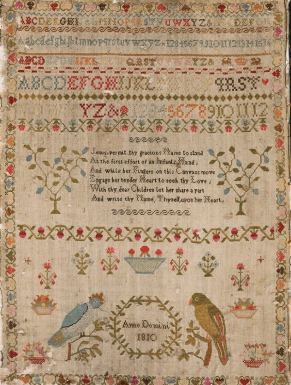The sampler is divided in thrids with an alphabet at the top, at center is a panel with verse. The bottom third has two birds on each side of the year made