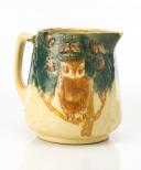 Cream colored Roseville pitcher with Brown decorated owl sitting on a limb in a tree. Top of the Pitcher is green.