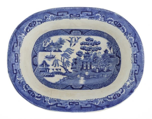 Oblong glazed stoneware mold-made dish with an off-white clay body and a white and blue glaze in the Blue Willow pattern.