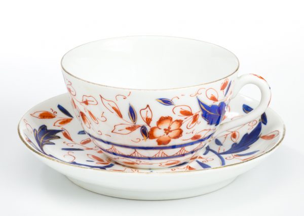 A cup and saucer decorated with flowers made by dipping the finger in glaze and leaving a fingerprint that is then outlined with a brush.