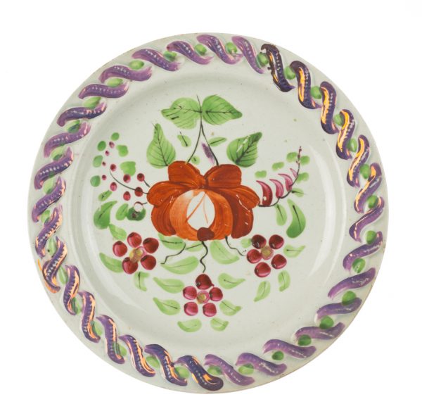 A small luster creamware plate with a raised ribbon border and painted floral spray at center.