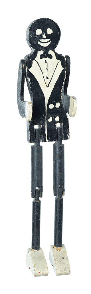 A toy of a man in a black suit, white shirt and shoes, black tie. He has articulated joints
