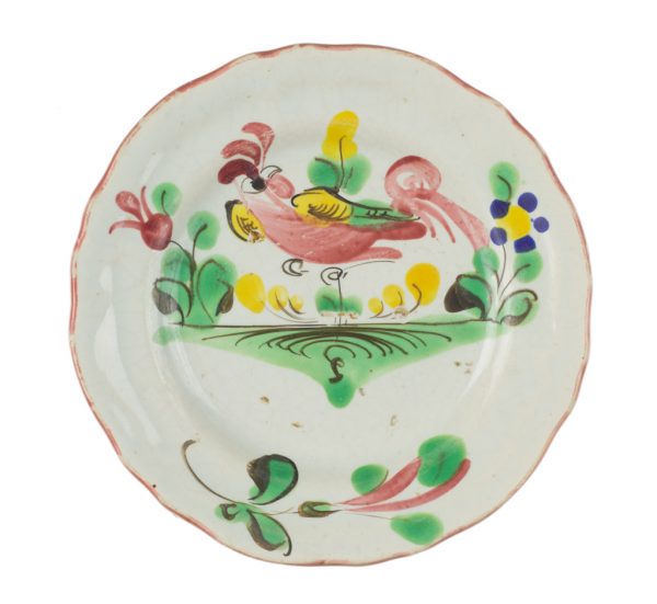 A small white dish with painted pink peafowl over green grass and plants.