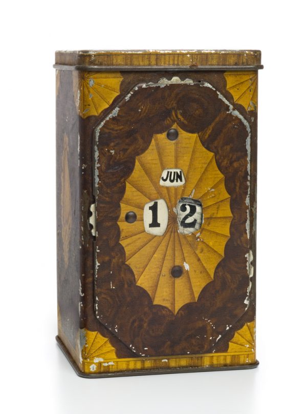 A tin box in green and yellow. One side has an adjustable calendar.