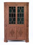 A red painted cupboard with carved overlays. The doors have 15 panes on each side.