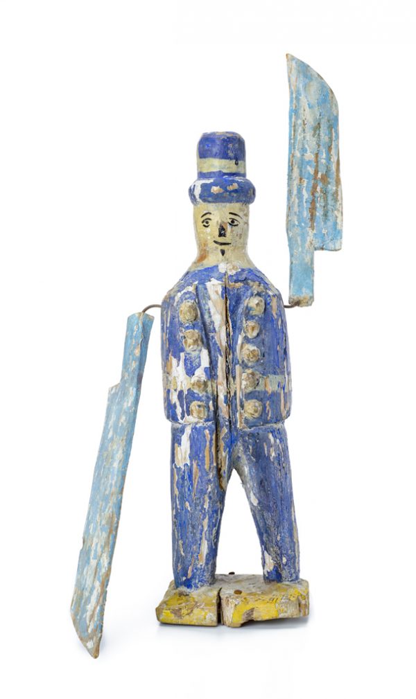 Whirligig man wears a blue suit and top hat. He has a face on both sides and knives for arms