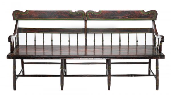 A spindle-backed bench that has a low, flat seat, eight turned legs that are connected with staggered stretchers, a crest and midrail at the seat back, and two curved arms. The mid-rail is connected to the seat with a series of 14 turned spindles. The bench is painted overall with a faux wood grain pattern as well as green and yellow banding.