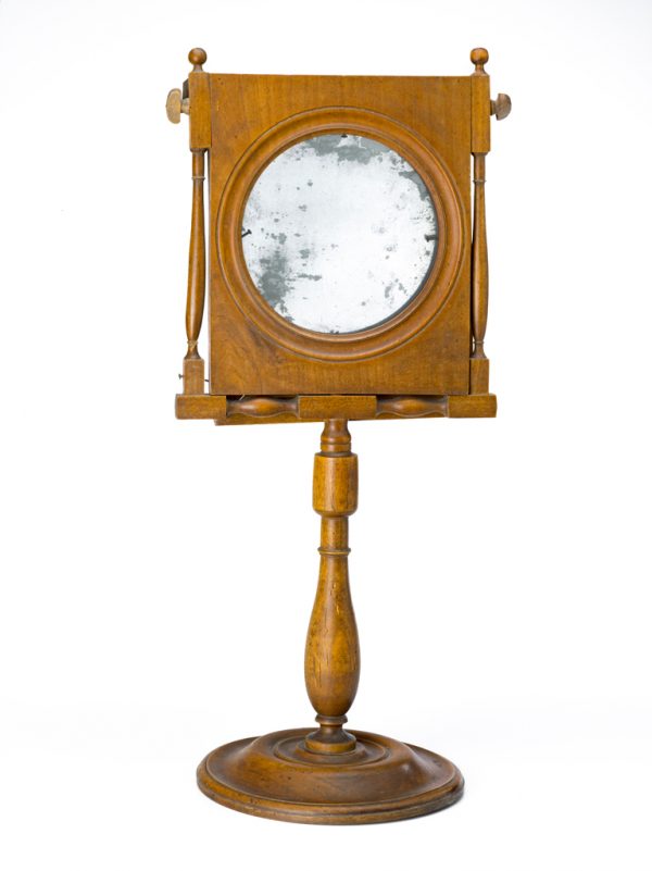 A  freestanding shaving mirror with a disk base, turned post, and rectangular two-part
frame. A magnifying glass is backed by a slivered glass. These are on hinges at the top so that the glass can be used separate from the magnifier.