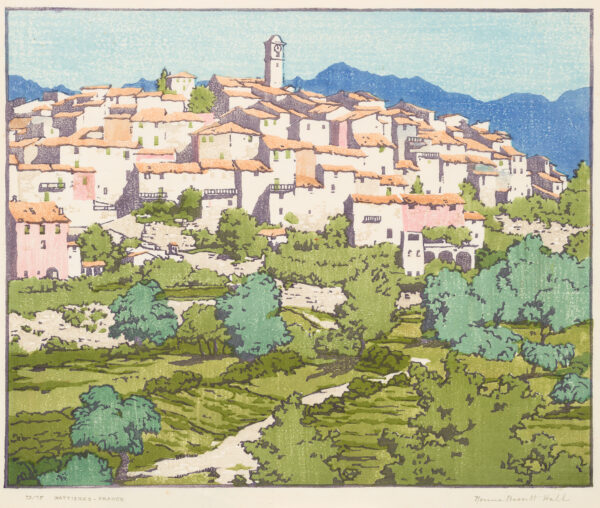 A hill has green trees below and crowded white houses with red roofs above. There is a tower at the center a deep blue mountains in the distance.