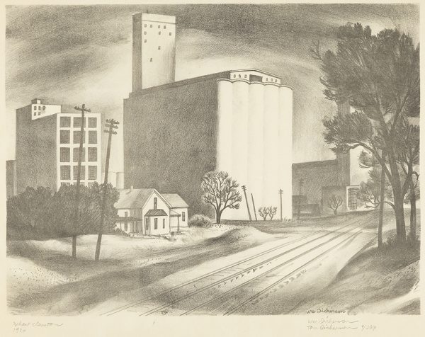 A road leads from the bottom left to the center where a large wheat elevator stands. Trees are on the right side and smaller buildings are on the left.