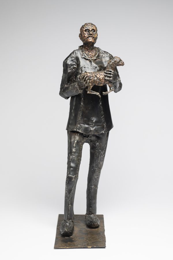 A shepherd stand holding a lamb.